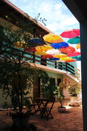 A building with a staircase, outdoor seating, and multiple colorful umbrellas. - Pouso De Icaro (Paraty)