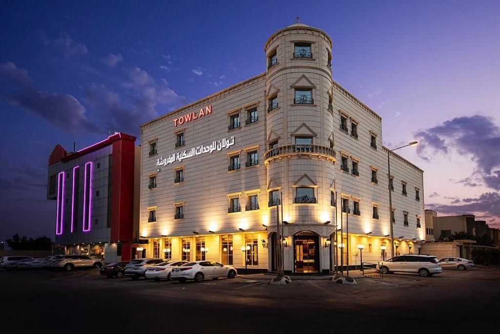 A hotel with a prominent 'TOWLAN' sign, multiple floors, and a parking lot with several cars.