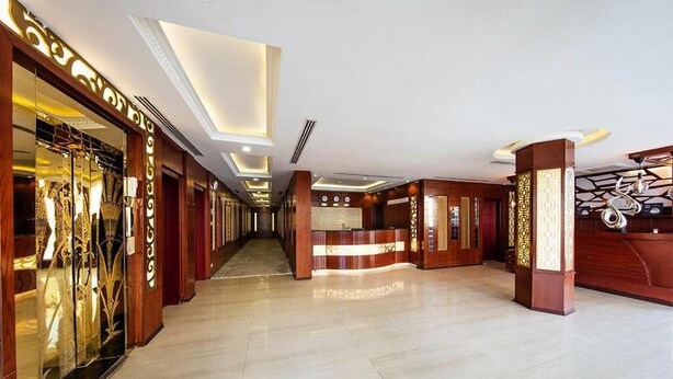 Um saguão de hotel com balcão de recepção, um corredor comprido e uma vitrine de vidro.