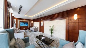 Uma sala de estar ampla com uma grande televisão de tela plana, assentos confortáveis e um painel decorativo na parede.