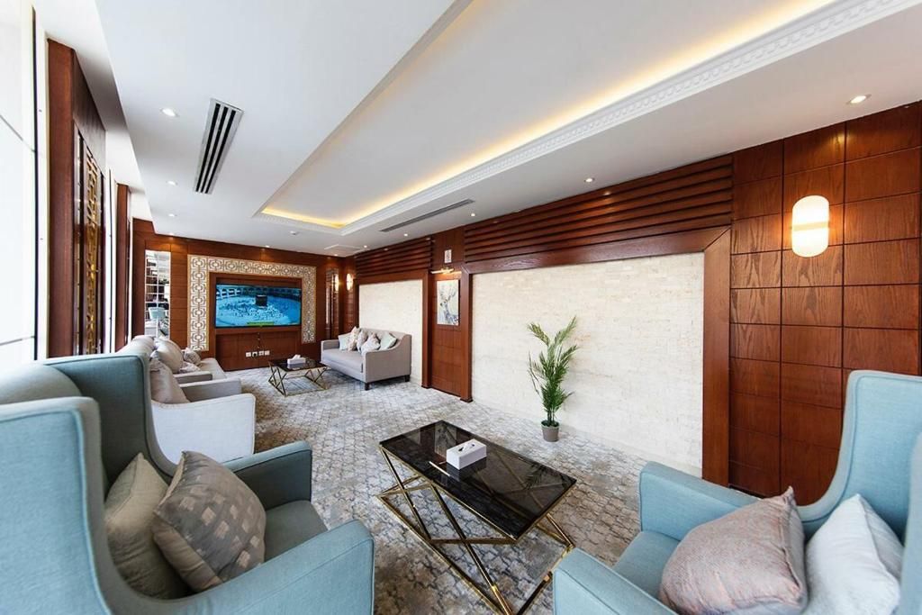 A spacious living area with a large flat-screen TV, comfortable seating, and a decorative wall panel.
