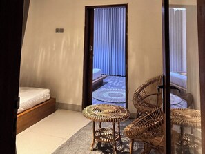 A room with a bed, a small round table, and two wicker chairs. - Volcano Side Kintamani Bali By Zuzu (Kintamani)