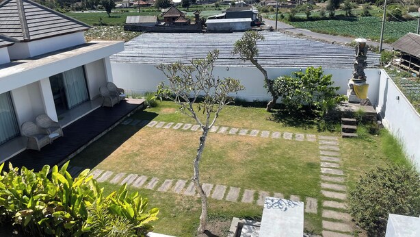 A residential area with a modern house, a small garden, and a view of a village in the background. - Volcano Side Kintamani Bali By Zuzu (Kintamani)