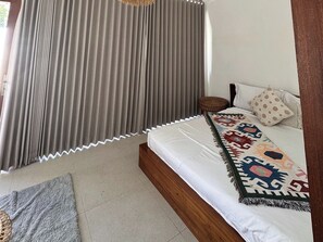 A bedroom with a bed, curtains, a patterned throw, and a small stool. - Volcano Side Kintamani Bali By Zuzu (Kintamani)
