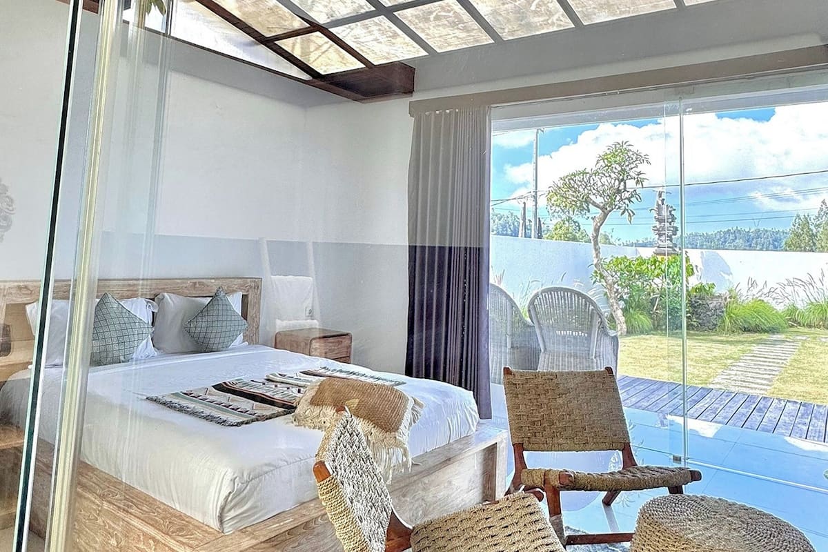 Quarto com cama, mesas de cabeceira, janela com vista e cadeiras de vime.