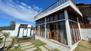 A modern two-story house with large windows, a balcony, and a well-maintained lawn. - Volcano Side Kintamani Bali By Zuzu (Kintamani)