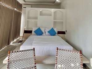 A hotel room with a bed, two blue pillows, a macrame chair, and a wooden headboard. - Volcano Side Kintamani Bali By Zuzu (Kintamani)