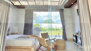 Un dormitorio moderno con una cama grande, una silla, una mesita y un televisor.