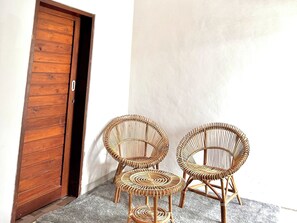 A wooden door, three wicker chairs, and a grey carpet. - Volcano Side Kintamani Bali By Zuzu (Kintamani)