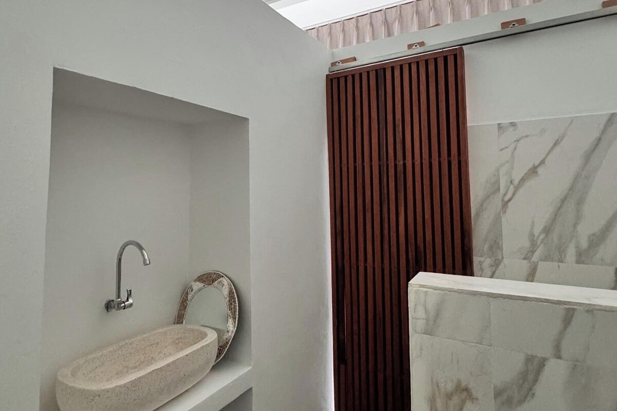 A bathroom with a marble sink, a shower curtain, and a marble wall.