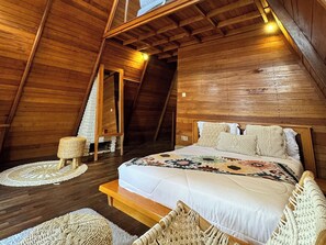 A wooden interior with a bed, a small seating area, and a staircase. - Volcano Side Kintamani Bali By Zuzu (Kintamani)