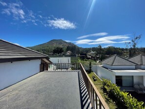 A residential area with a clear sky, a mountain in the background, and houses with sloped roofs. - Volcano Side Kintamani Bali By Zuzu (Kintamani)