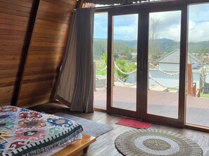 A room with a bed, a bench, a rug, and a view through a sliding door to a deck with a rope barrier. - Volcano Side Kintamani Bali By Zuzu (Kintamani)