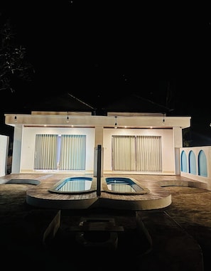 A modern building with two large windows, a pool area, and a covered outdoor space.