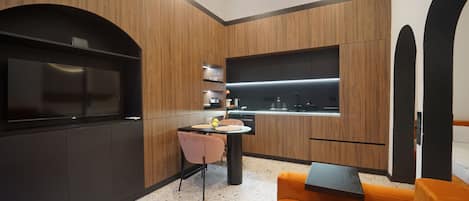A modern kitchen with wooden cabinetry, a built-in oven, and a dining area with a table and chairs.