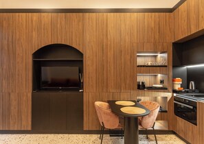 Une cuisine moderne avec un lambris en bois, une arche noire, une table à manger avec deux chaises et des appareils électroménagers intégrés.