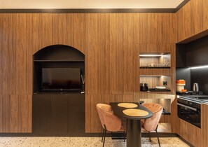 A modern kitchen with wooden paneling, a black archway, a dining table with two chairs, and built-in appliances. - Jais Home-moon Apartment-muzeului Square-old Town (Cluj-Napoca)