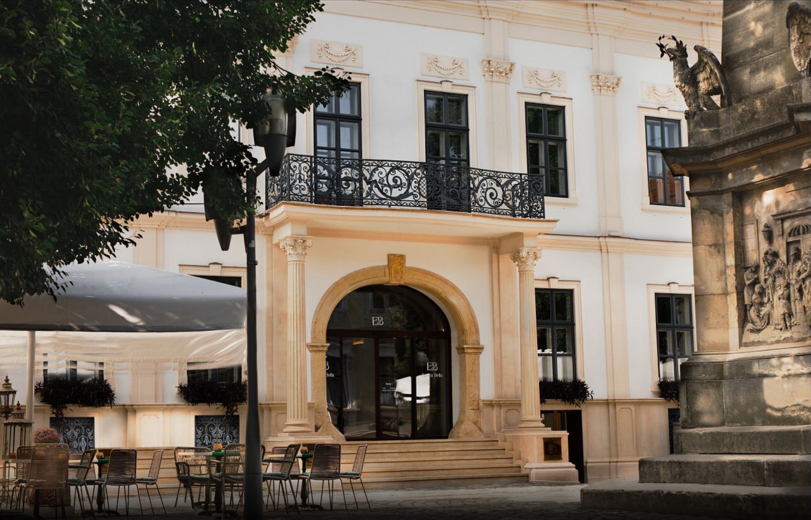 A building with a balcony, a large arched entrance, and outdoor seating.