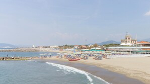 A beach with rows of sun loungers and umbrellas, a pier, and a building with a dome and flag. - 2 bedroom gorgeous apartment in Marina di Massa (Marina di Massa)
