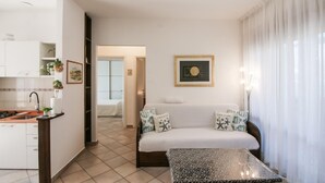 A modern living room with a sofa, a coffee table, and a kitchen area with a stove. - 2 bedroom gorgeous apartment in Marina di Massa (Marina di Massa)