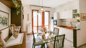 A dining area with a glass table, chairs, and a kitchen in the background. - 2 bedroom gorgeous apartment in Marina di Massa (Marina di Massa)
