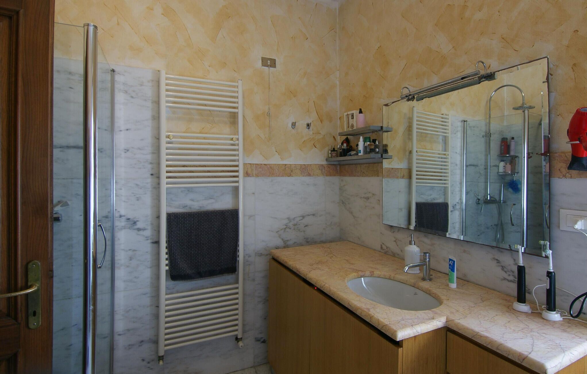 A bathroom with a glass shower enclosure, a sink with a mirror, and a towel rack.