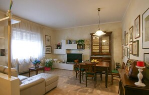 A living room with a sofa, dining table, chairs, a TV, and a cabinet with glass doors.