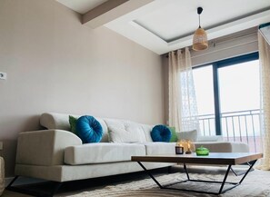 A modern living room with a sofa, a coffee table, and a hanging light fixture. - Tivat Terrace Suites (Tivat)