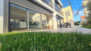 A modern building with large sliding glass doors, a flat roof, and a well-maintained lawn. - Tivat Terrace Suites (Tivat)
