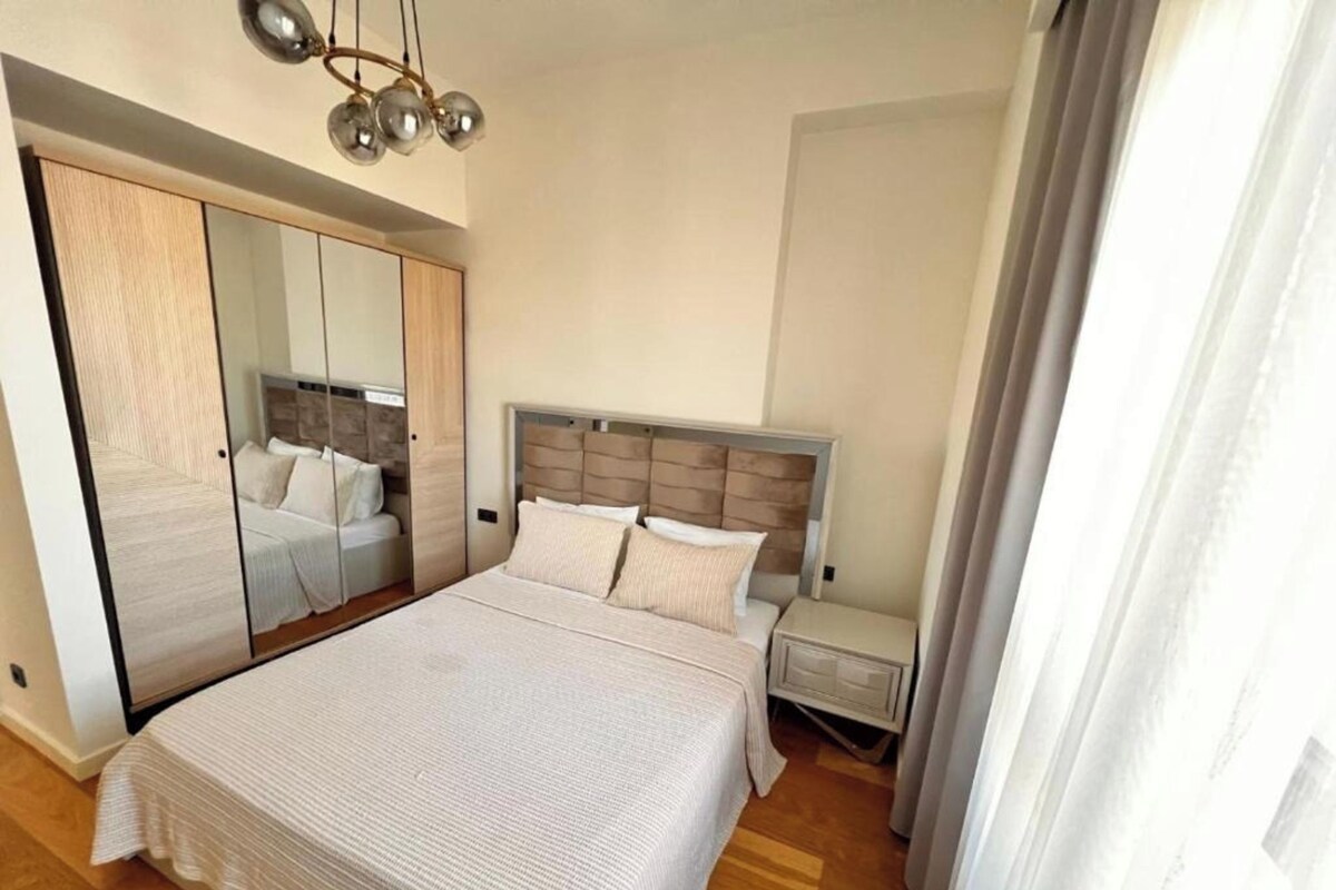 Un dormitorio con una cama grande, un armario, una mesita de noche y un espejo.