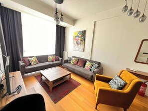Una sala de estar con un juego de sofá, una mesa de centro, un sillón amarillo y un cuadro en la pared.
