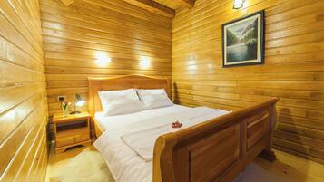 Una habitación de cabaña de madera con una cama, mesita de noche, lámpara y un cuadro enmarcado en la pared.