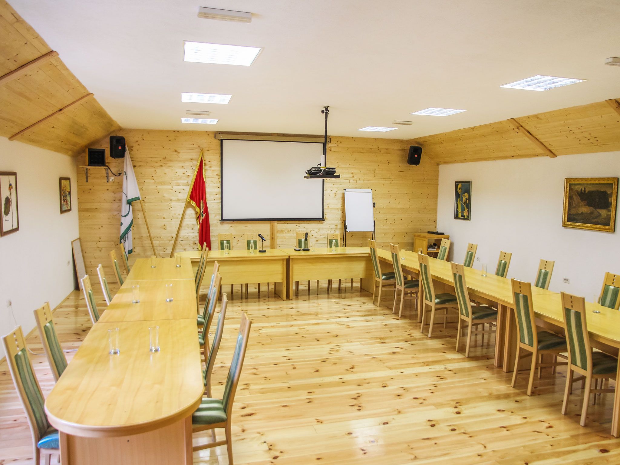 A conference room with a long table, chairs, a whiteboard, and a projector.