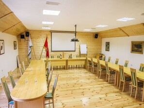 Un salón de conferencias con una larga mesa, sillas, una pizarra y un proyector.