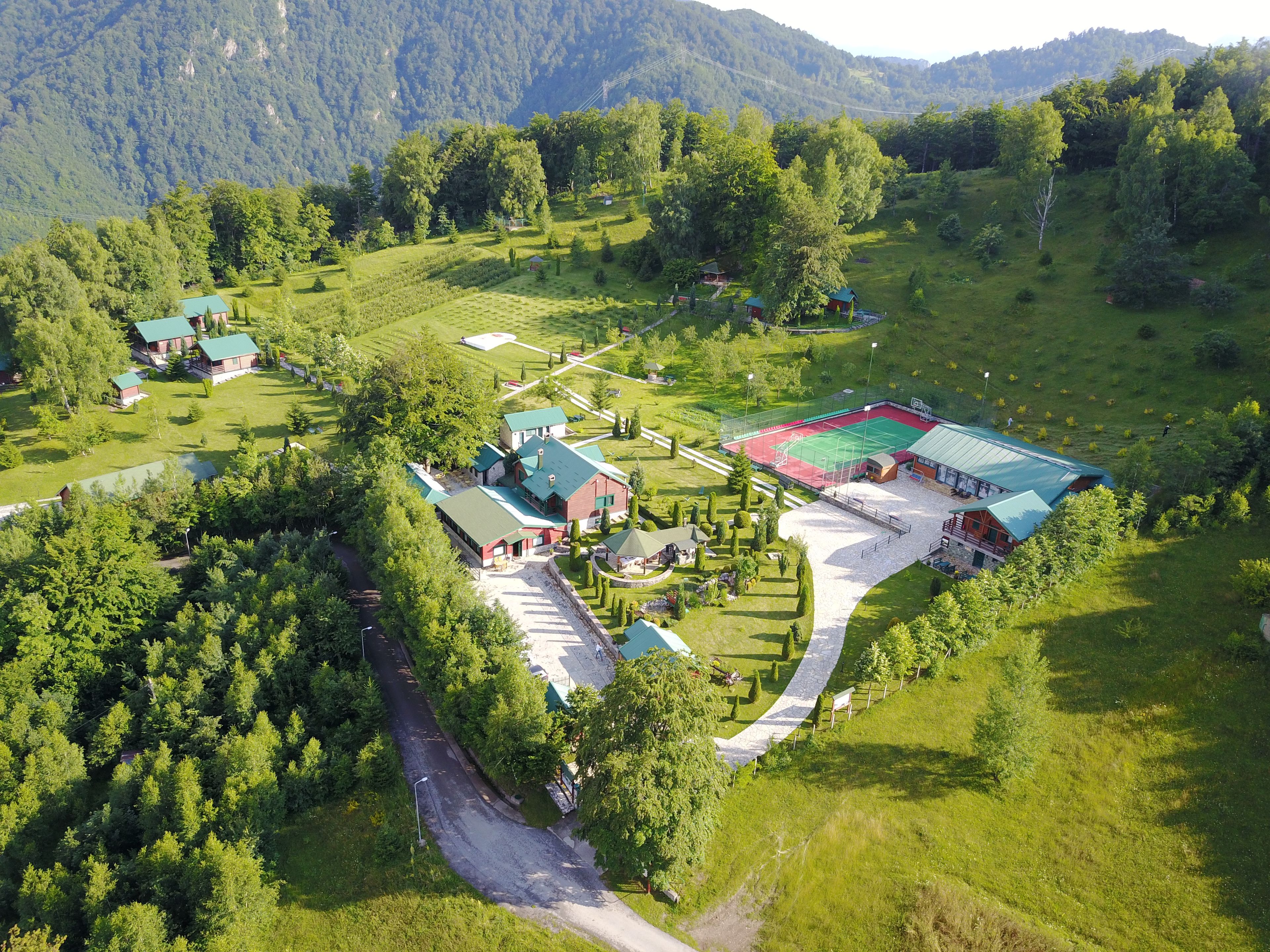 An aerial view of a rural property with multiple buildings, a sports court, and a winding road.