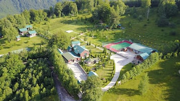 An aerial view of a rural property with multiple buildings, a sports court, and a winding road.
