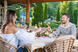 Una pareja cenando al aire libre en una mesa con vistas a un jardín.
