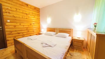 A wooden-paneled bedroom with a bed, two bedside tables, and a nightstand.