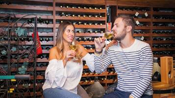 A man and a woman sitting in a wine cellar with wine racks in the background.