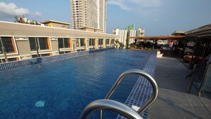 A swimming pool with metal railings, surrounded by a tiled deck and a building with multiple windows and balconies. - The Pad Co-living (Cebu City)