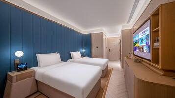 Quarto de hotel com uma cama grande, mesas de cabeceira, uma TV e um armário de madeira.