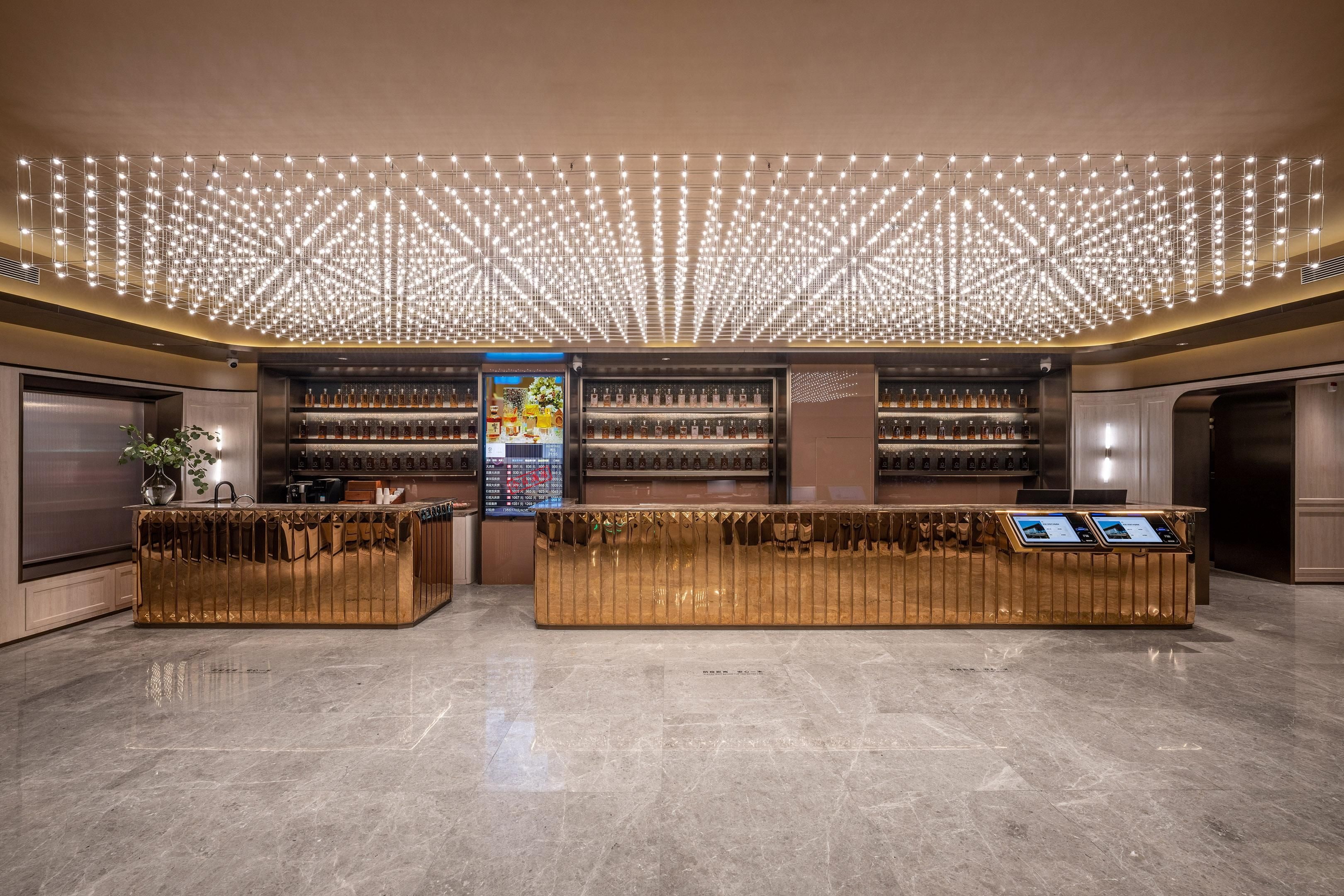 A hotel lobby with a reception desk, a bar area, and a large chandelier.