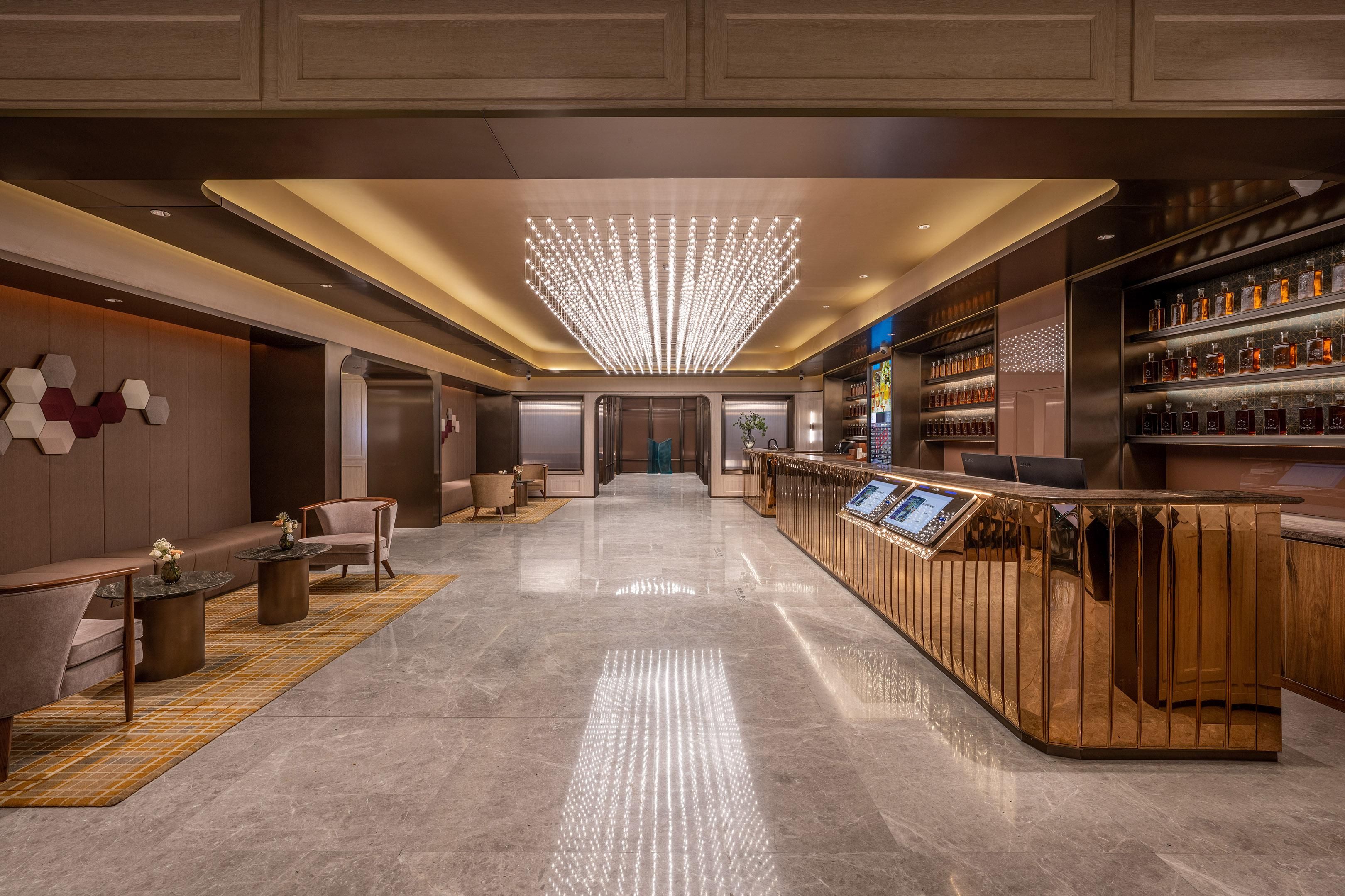 A modern lobby with a bar area, seating, and a decorative ceiling light.