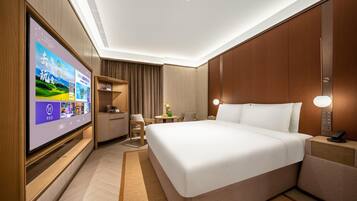 Una habitación de hotel con una televisión de pantalla plana grande, una cama, un escritorio y una silla.