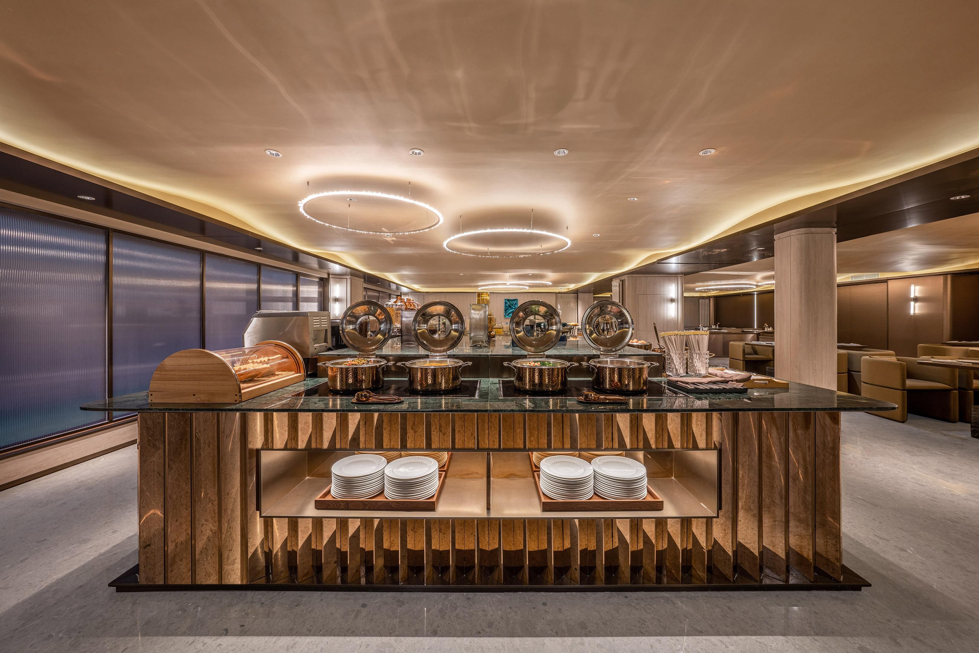 Disposição moderna de buffet, com ilha central, diversas estações de serviço e design de interiores contemporâneo.