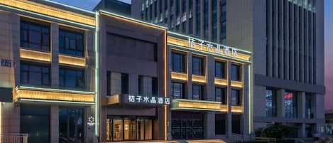 Um hotel com fachada moderna, vários andares e sinalização iluminada.