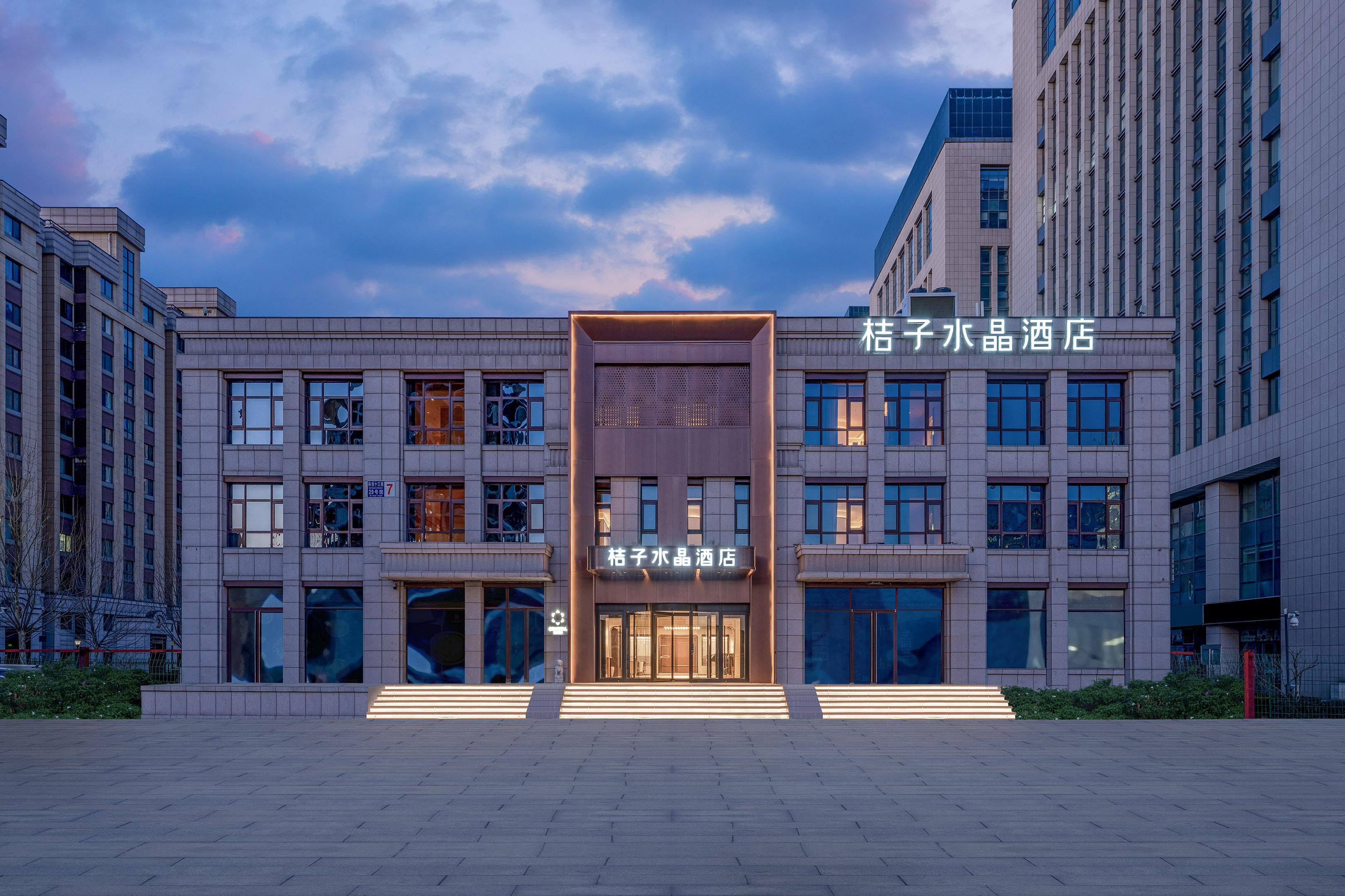 Un hotel con una facciata moderna, ampie finestre e un ingresso centrale con gradini.