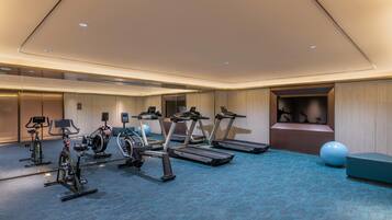 A gym with treadmills, stationary bikes, and exercise balls.