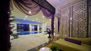 Un vestíbulo de hotel con piscina, sofá y una pared decorativa.