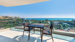 Un balcón con mesa y sillas, que ofrece vistas al mar y edificios circundantes.